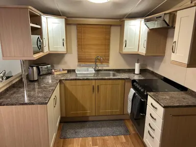 a kitchen with wooden cabinets and a sink and a stove at Havah’s in Saint Osyth