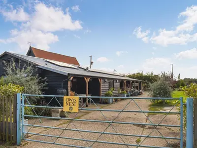 a house with a gate with a sign that reads own nest at Owls Nest in Stradbroke