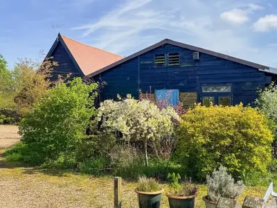 a blue house with plants in front of it at Owls Nest in Stradbroke