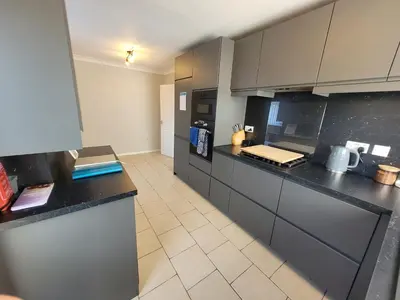 a large kitchen with black counter tops and appliances at Modern 4-Bedroom Contractor Base in Lexden with Parking, WiFi & Quick Access to Sites- Catchpole Stays in Lexden