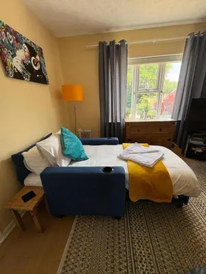 a bedroom with a bed and a blue couch at Home from Home in our Self-Contained Annexe in Radwinter