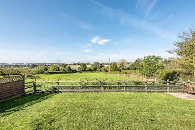 a wooden fence in a field with a grass field at The Cabin, Parham in Woodbridge