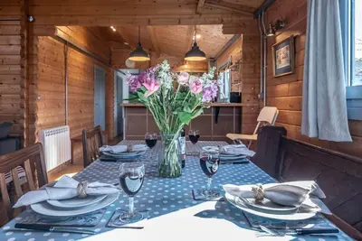 a dining table with a vase of flowers on it at The Cabin, Parham in Woodbridge