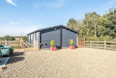 a black shed with two potted plants in a yard at The Cabin, Parham in Woodbridge