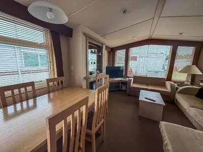 a kitchen and living room with a dining table and a couch at Great Caravan On A Family Holiday Park In Essex, Ref 37055G in Clacton-on-Sea