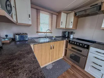 a kitchen with a sink and a stove top oven at Great Caravan On A Family Holiday Park In Essex, Ref 37055G in Clacton-on-Sea