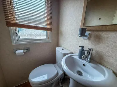 a bathroom with a white toilet and a sink at Great Caravan On A Family Holiday Park In Essex, Ref 37055G in Clacton-on-Sea