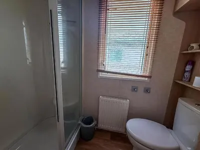 a bathroom with a shower and a toilet and a window at Great Caravan On A Family Holiday Park In Essex, Ref 37055G in Clacton-on-Sea