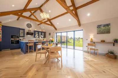 a kitchen and living room with blue cabinets and a table and chairs at Large immaculate rural conversion - The Milking Parlour in Ipswich