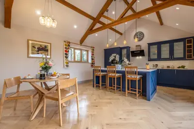 a kitchen with blue cabinets and a table and chairs at Large immaculate rural conversion - The Milking Parlour in Ipswich