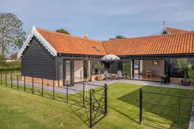a house with a fence in the yard at Large immaculate rural conversion - The Milking Parlour in Ipswich
