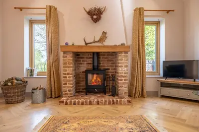 a living room with a fireplace and a tv at Large immaculate rural conversion - The Milking Parlour in Ipswich