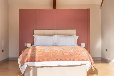 a bedroom with a large bed with red walls at Large immaculate rural conversion - The Milking Parlour in Ipswich