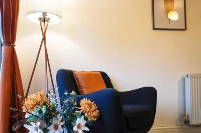 a living room with a blue chair and a lamp at Entire House in Ipswich - Handford in Ipswich