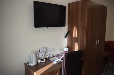 a room with a desk with a television on the wall at Star Anglia Hotel City Center by OYO in Colchester