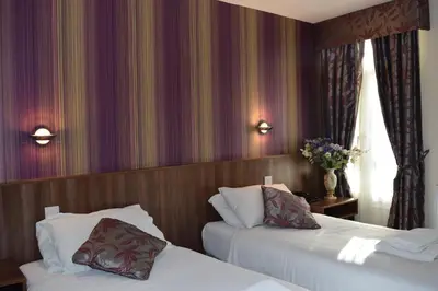 a hotel room with two beds and flowers on the wall at Star Anglia Hotel City Center by OYO in Colchester