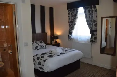 a bedroom with a bed and a mirror and a window at Star Anglia Hotel City Center by OYO in Colchester