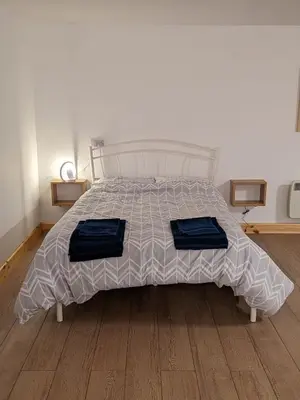 a bedroom with a bed with two blue pillows on it at The Annex in Felixstowe