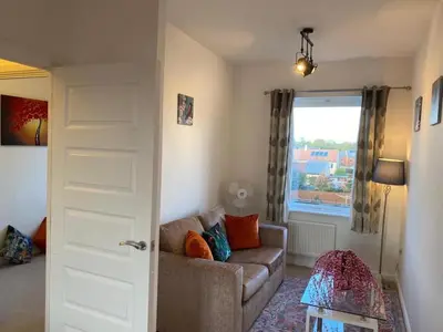 a living room with a couch and a window at Homely, Cosy & Contemporary 4 BDR house with Garden & Parking 5 mins drive to Addenbrookes & Papworth hospitals & Bio Medical campus in Cambridge