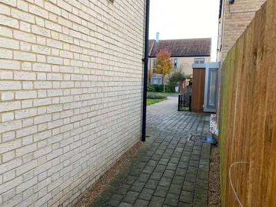 a brick alleyway next to a brick building at Homely, Cosy & Contemporary 4 BDR house with Garden & Parking 5 mins drive to Addenbrookes & Papworth hospitals & Bio Medical campus in Cambridge