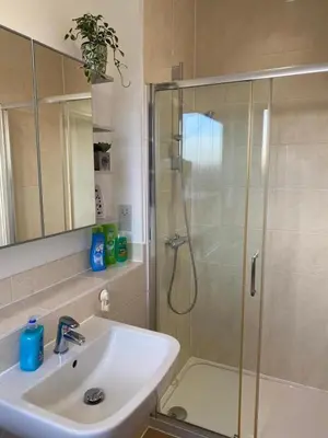 a bathroom with a sink and a shower with a glass door at Homely, Cosy & Contemporary 4 BDR house with Garden & Parking 5 mins drive to Addenbrookes & Papworth hospitals & Bio Medical campus in Cambridge