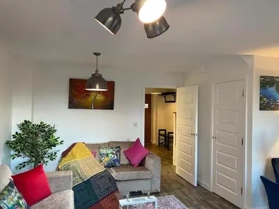 a living room with a couch and a ceiling fan at Homely, Cosy & Contemporary 4 BDR house with Garden & Parking 5 mins drive to Addenbrookes & Papworth hospitals & Bio Medical campus in Cambridge