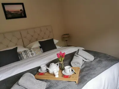 a bed with a tray with tea sets and flowers on it at Woodpeckers - Alresford Essex in Alresford