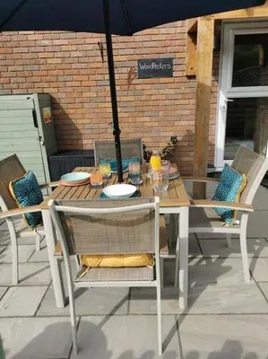 a table and chairs with an umbrella on a patio at Woodpeckers - Alresford Essex in Alresford