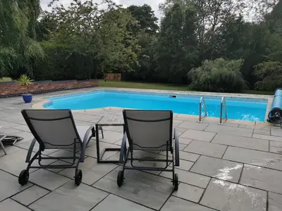 two chairs sitting in front of a swimming pool at Woodpeckers - Alresford Essex in Alresford