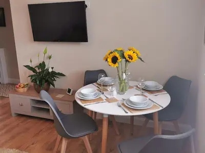 a table with chairs and a white table with sunflowers on it at Woodpeckers - Alresford Essex in Alresford