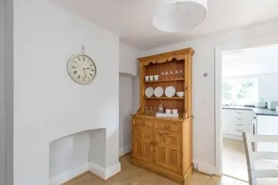 a kitchen with a clock on the wall and a wooden cabinet at Victorian 2 Bedroom Home near the river Cam in Cambridge