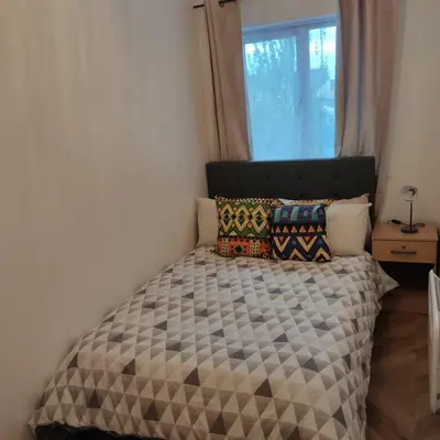 a small bedroom with a bed with a window at Ratcliffe Apartment in Colchester