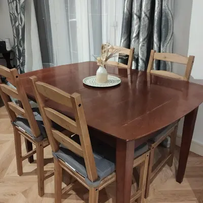 a wooden table with four chairs and a vase on it at Ratcliffe Apartment in Colchester