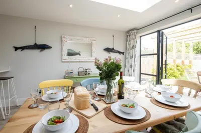 a dining room with a wooden table with dishes on it at 17 Park Lane, Beautiful 4 bedroom house in the seaside town of Aldeburgh - Maximum occupancy of 7 guests - Aldeburgh Coastal Cottages in Aldeburgh