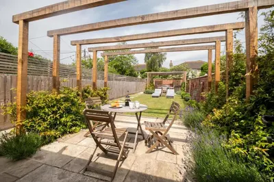 a patio with a table and chairs in a garden at 17 Park Lane, Beautiful 4 bedroom house in the seaside town of Aldeburgh - Maximum occupancy of 7 guests - Aldeburgh Coastal Cottages in Aldeburgh