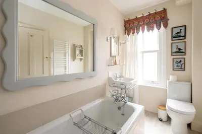 a bathroom with a tub and a sink and a mirror at 17 Park Lane, Beautiful 4 bedroom house in the seaside town of Aldeburgh - Maximum occupancy of 7 guests - Aldeburgh Coastal Cottages in Aldeburgh