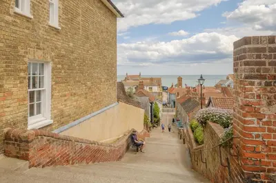 a narrow alleyway between two brick buildings with people sitting at 17 Park Lane, Beautiful 4 bedroom house in the seaside town of Aldeburgh - Maximum occupancy of 7 guests - Aldeburgh Coastal Cottages in Aldeburgh