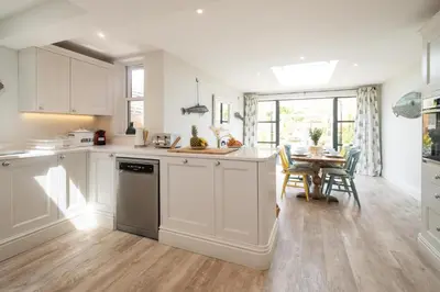 a kitchen with white cabinets and a dining room with a table at 17 Park Lane, Beautiful 4 bedroom house in the seaside town of Aldeburgh - Maximum occupancy of 7 guests - Aldeburgh Coastal Cottages in Aldeburgh