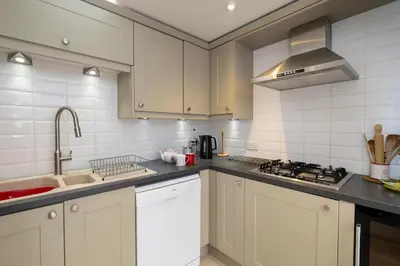 a kitchen with white cabinets and a stove top oven at Pantiles in Aldeburgh