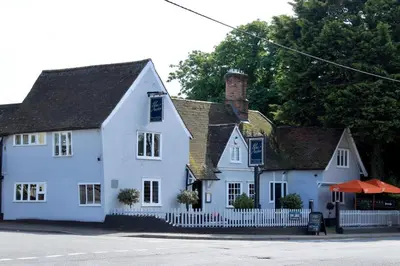 a white house with a white fence in front of it at The Blue Anchor Feering in Colchester