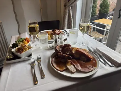 a table with a plate of food and glasses of wine at The Blue Anchor Feering in Colchester
