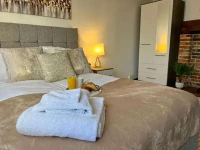 a bed with towels and a cup and a cat laying on it at Duchess Apt 1 Serviced 3BR Apartment in Colchester Perfect for Contractors,Temporary Housing, Relocations,Free Wifi, Secure Parking in Colchester