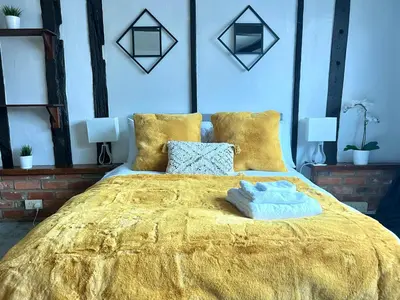 a bedroom with a large gold bed with two pillows at Duchess Apt 1 Serviced 3BR Apartment in Colchester Perfect for Contractors,Temporary Housing, Relocations,Free Wifi, Secure Parking in Colchester