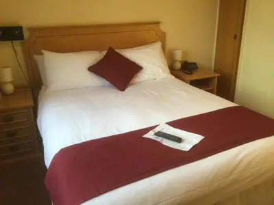 a bed with a remote control on top of it at Nyton Hotel in Ely