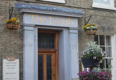 a building with two flower pots in front of a door at Lamb Hotel by Greene King Inns in Ely