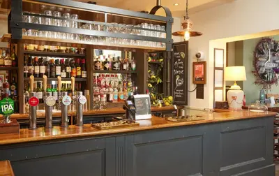 a bar with a lot of bottles of alcohol at Lamb Hotel by Greene King Inns in Ely