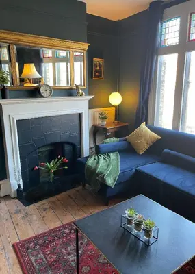 a living room with a blue couch and a fireplace at Elegant Luxury City Centre Apartment on On Mill Rd - Walk to Station and City Centre in Cambridge