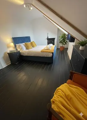 a attic bedroom with two beds and a staircase at Elegant Luxury City Centre Apartment on On Mill Rd - Walk to Station and City Centre in Cambridge