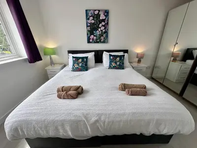 a bedroom with a large white bed with two brown pillows at Award Winning Beautiful House in South Cambridge, 14-Min Drive to the City Centre, Free Parking, No Sofabeds, Sleeps 6 in Cambridge
