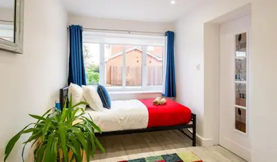 a bedroom with a bed with blue curtains and a window at Award Winning Beautiful House in South Cambridge, 14-Min Drive to the City Centre, Free Parking, No Sofabeds, Sleeps 6 in Cambridge